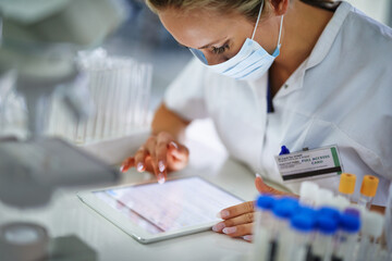 Checking through her findings. A young researcher recording her results on a tablet in t he lab.