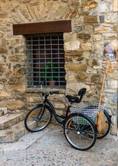 Fototapeta na wymiar Classic black tricycle, with metal basket, parked in an old mediterranean street