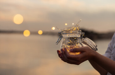 Jar with lights on the beach in summer sunset. Sunset colors. Selective focus.