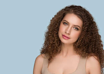 Curly long brunette hair woman beauty portrait, female glamour face. Color backgound blue