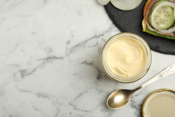 Obraz na płótnie Canvas Jar of delicious mayonnaise near fresh sandwich on white marble table, flat lay. Space for text