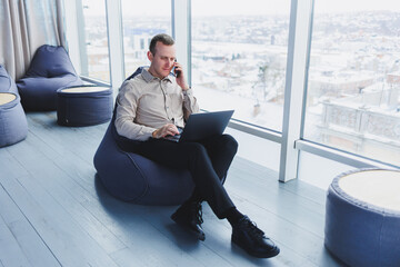 Young smart male businessman is sitting in the office and working on a project related to public...