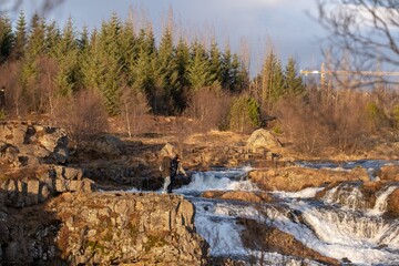Besucher am Kermóafoss Wasserfall im Elliðaárdalur, einem kleinen Tal des Flusses Elliðaá, in Reykjavik
