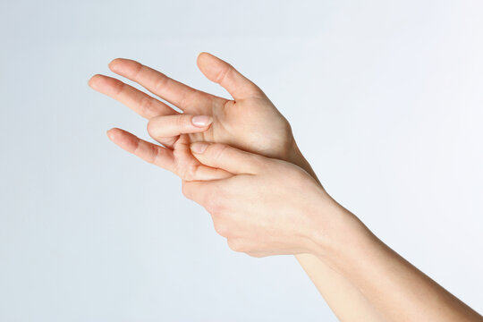 Woman with trigger finger condition on light background, closeup