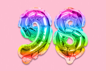 Rainbow foil balloon number, digit ninety eight on a pink background. Birthday greeting card with inscription 98. Top view. Numerical digit. Celebration event, template.