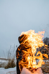 burning Maslenitsa doll on snow in the dried grass