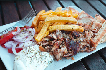 Traditional greek dish gyro on white plate, on wooden table.Delicious food in Greece.Close-up
