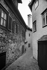 Black and white photo. Narrow street between european buildings.