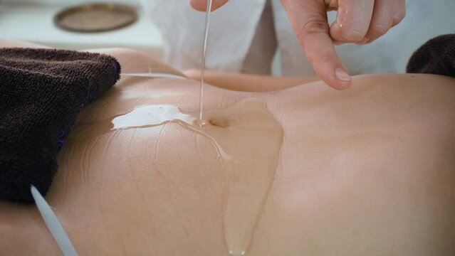 Pouring massage oil on attractive belly of young slim woman. Concept of body care and alternative medicine