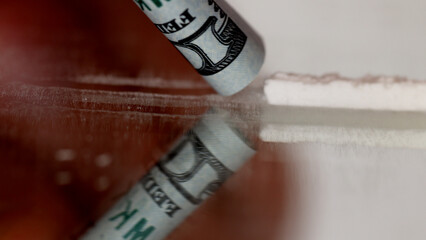 Cocaine junkie snorting line of coke with rolled US dollar bill.
