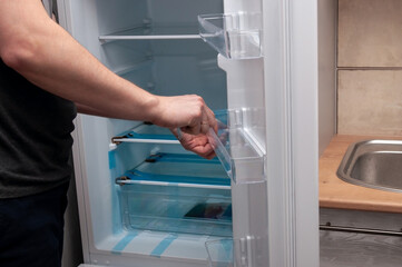 A man installs a shelf in a new refrigerator