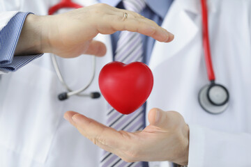 Medical worker protect plastic red heart, doctor cover heart model with hands