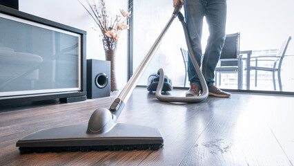 Man cleaning the house with a portable vacuum cleaner
