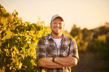 Farming is in my blood. Portrait of a happy farmer posing with his arms crossed in a vineyard. - Powered by Adobe