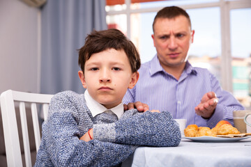 Portrait of upset father and offended son arguing in domestic interior