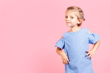 Portrait of cute little child girl wears blue dress while posing on pink studio background