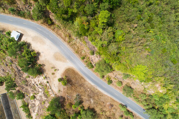 Fototapeta premium Travel on hilly road in spring aerial view road curve construction up to mountain Amazing top down image from drone camera