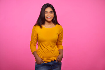 Adult woman in yellow outfit looking at camera and smiling with both hands in pockets