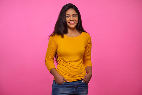 Adult Woman In Yellow Outfit Looking At Camera And Smiling With Both Hands In Pockets