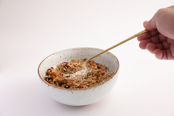 granola with milk with spoon isolated in white background