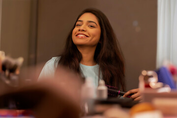 Young woman combing her hair in front of mirror