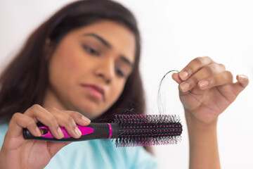 Close-up of Upset woman holding a comb with lost hair