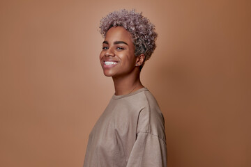 Young joyful confident African American woman student smiling with chin up being proud of himself wears casual oversize clothes posing on brown background in studio. Happiness people positive emotions