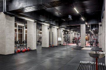 Exercise machines for physical training in spacious, well lit, empty gym interior with huge...