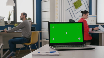 Close up of isolated green screen on laptop at empty desk. Device with mock up template and chroma...