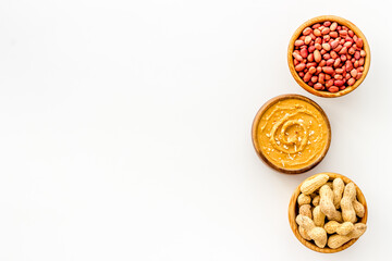 Bowls of homemade peanut butter and nuts on table, top view