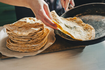 baker's hands are removing pita bread from a cast-iron frying pan.