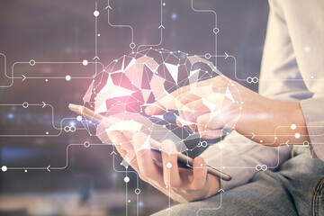 Double exposure of man's hand holding and using a digital device and brain hologram drawing. Data...