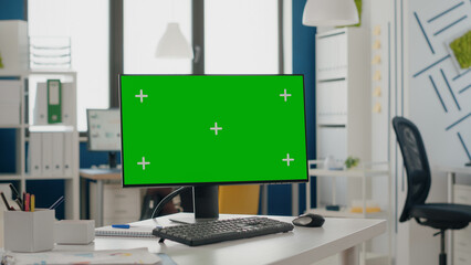 Close up of green screen on computer monitor at empty desk. Device with isolated mock up template...