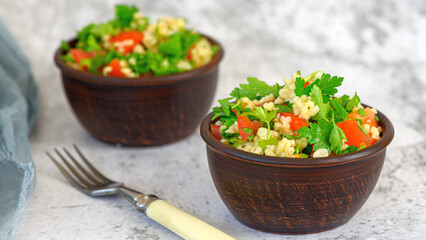 Tabbouleh salad with bulgur, parsley, spring onion and tomato in bowl on grey background