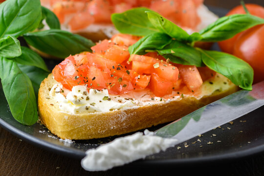 Tasty savory tomato Italian appetizers, or bruschetta, on slices of toasted baguette garnished with basil, close up