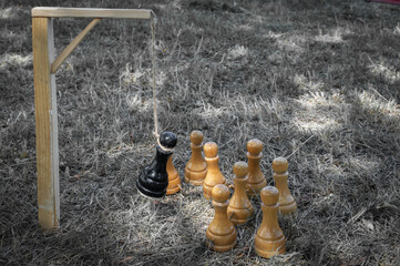 The black chess pawn is executed and hangs on the gallows in the noose and around the white pieces....