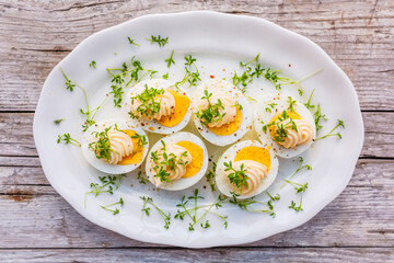 Boiled egg halves decorated with watercress. Easter egg snacks.