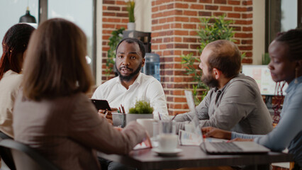 Close up of african american man working on business project with colleagues, planning marketing strategy for development and growth. Employee meeting to work on data analysis in boardroom.