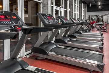 Lined contemporary speedwalks by the window in spacious, well lit, empty gym interior. Special modern equipment for physical training. Sport, fitness