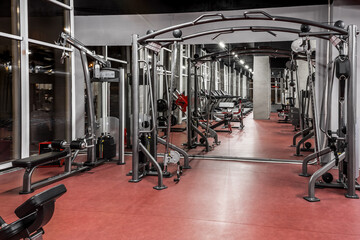 Fototapeta na wymiar Exercise machines for physical training in spacious, well lit, empty gym interior with huge mirror. Special modern equipment. Sport, fitness
