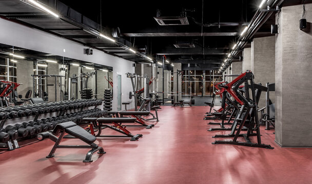 Exercise machines and racks with sets of black weights by the mirror in empty gym interior. Special equipment for physical training. Sport, fitness