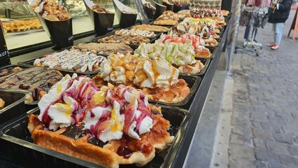 Belgian waffles with cream on top, with different fruits and different colored syrups.
