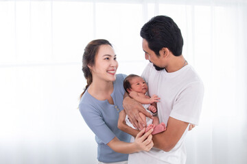Selective focus of Asian woman and man holding newborn baby at home. Happy family smiling with adorable infant, cheerful young parents holding little sweet toddler baby, love and happiness concept.