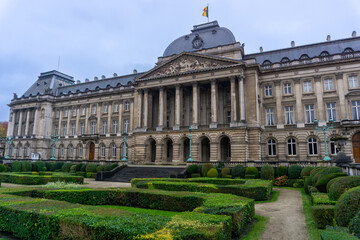 Royal Palace of Brussels seen from one of its doors, with the gardens in front, on a cloudy day.