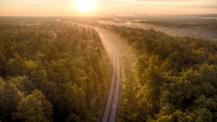 From a bird's eye view on the railway in the middle of the forest at dawn in autumn