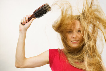 Blonde girl long blowing hair holds natural bristles brush