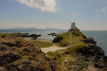 Old lighthouse in Anglesey with sand and greenery and rocks