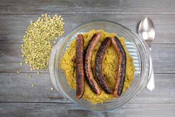 mashed split peas in a dish with fresh sausages