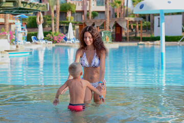Fototapeta na wymiar A young mother teaches her son to swim in the pool. Holidays Sharm El Sheikh
