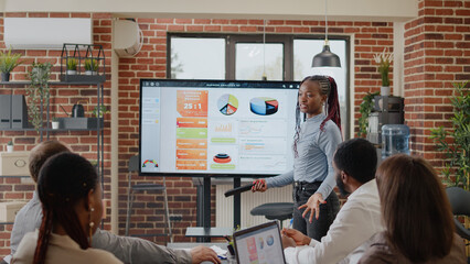 Close up of woman doing business presentation in boardroom, explaining charts analysis to workmates for comany development and growth. Employee presenting marketing strategy on screen.